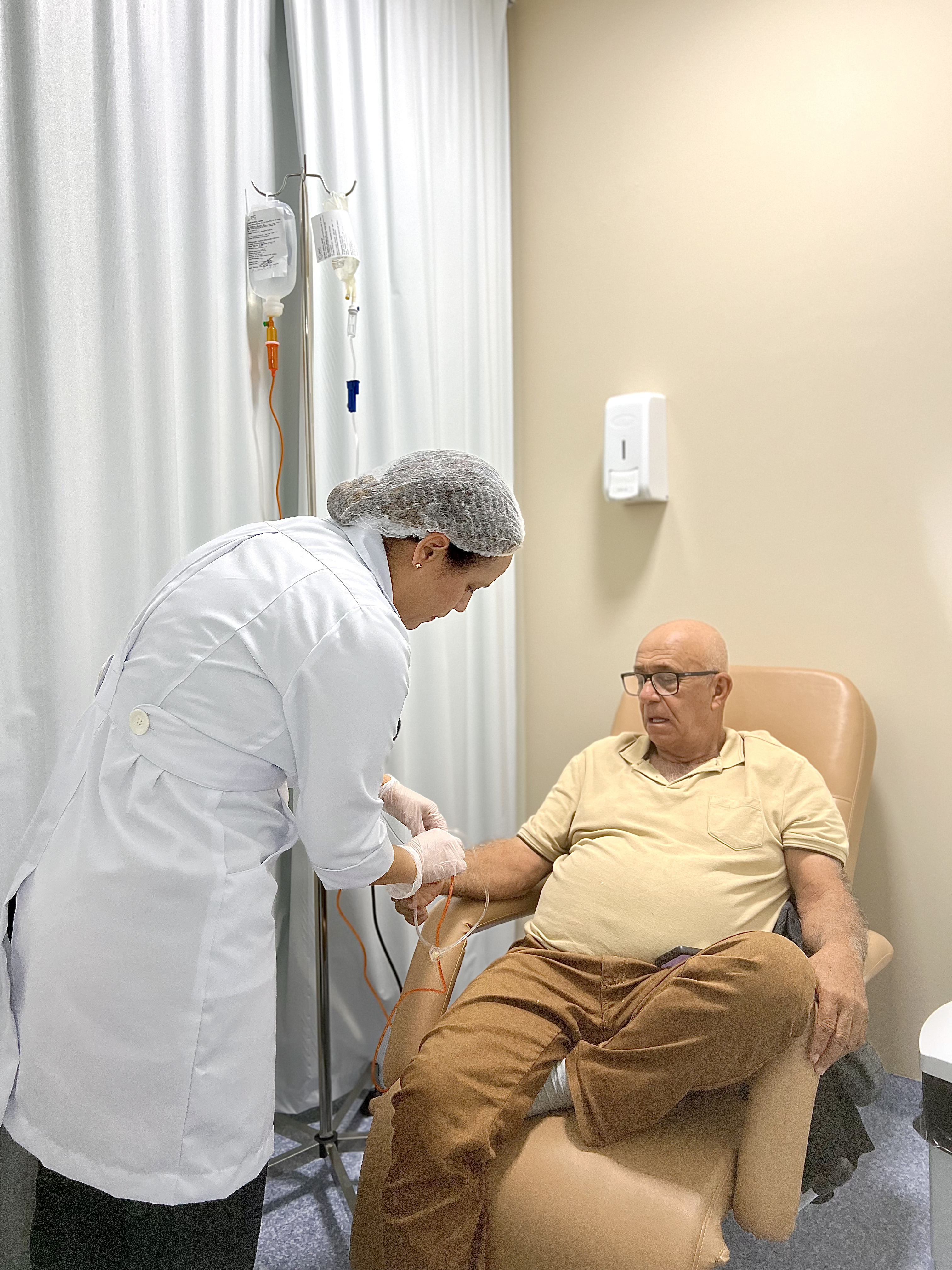 Enfermeira segurando a mão de uma paciente durante uma infusão na Clínica IMC
